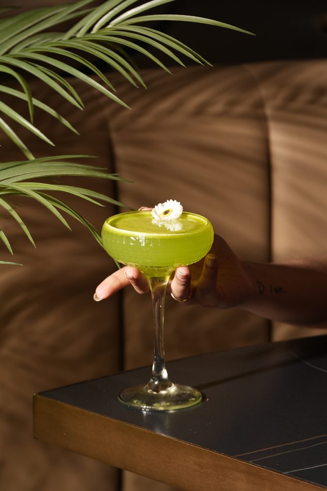 Bright green summer cocktail garnished with a white flower