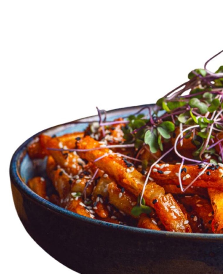 Bowl of sesame honey chilli fries topped with microgreens