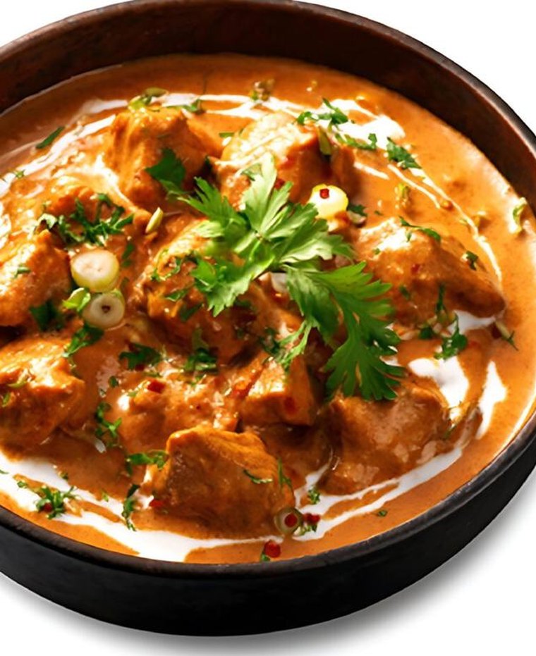 Butter chicken in a dark bowl with cream and coriander